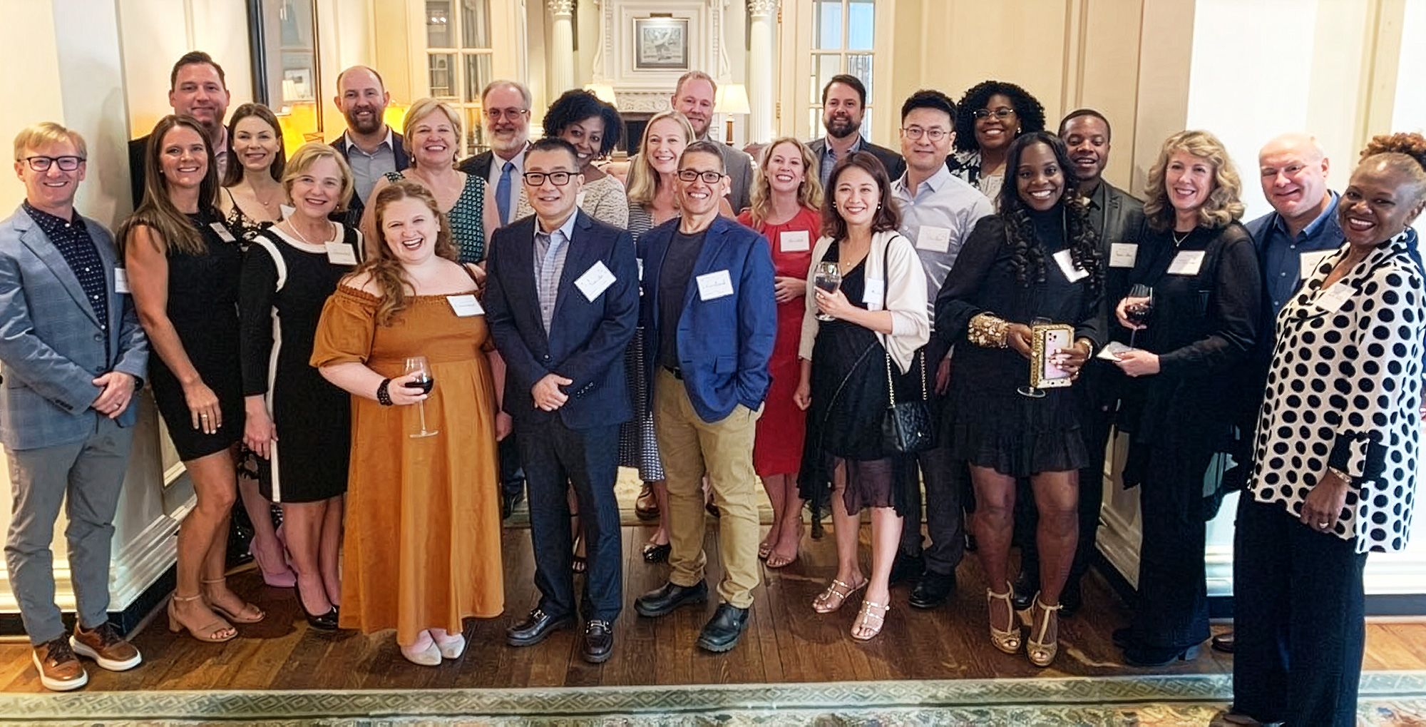 A group photo of approximately 25 people at a reception