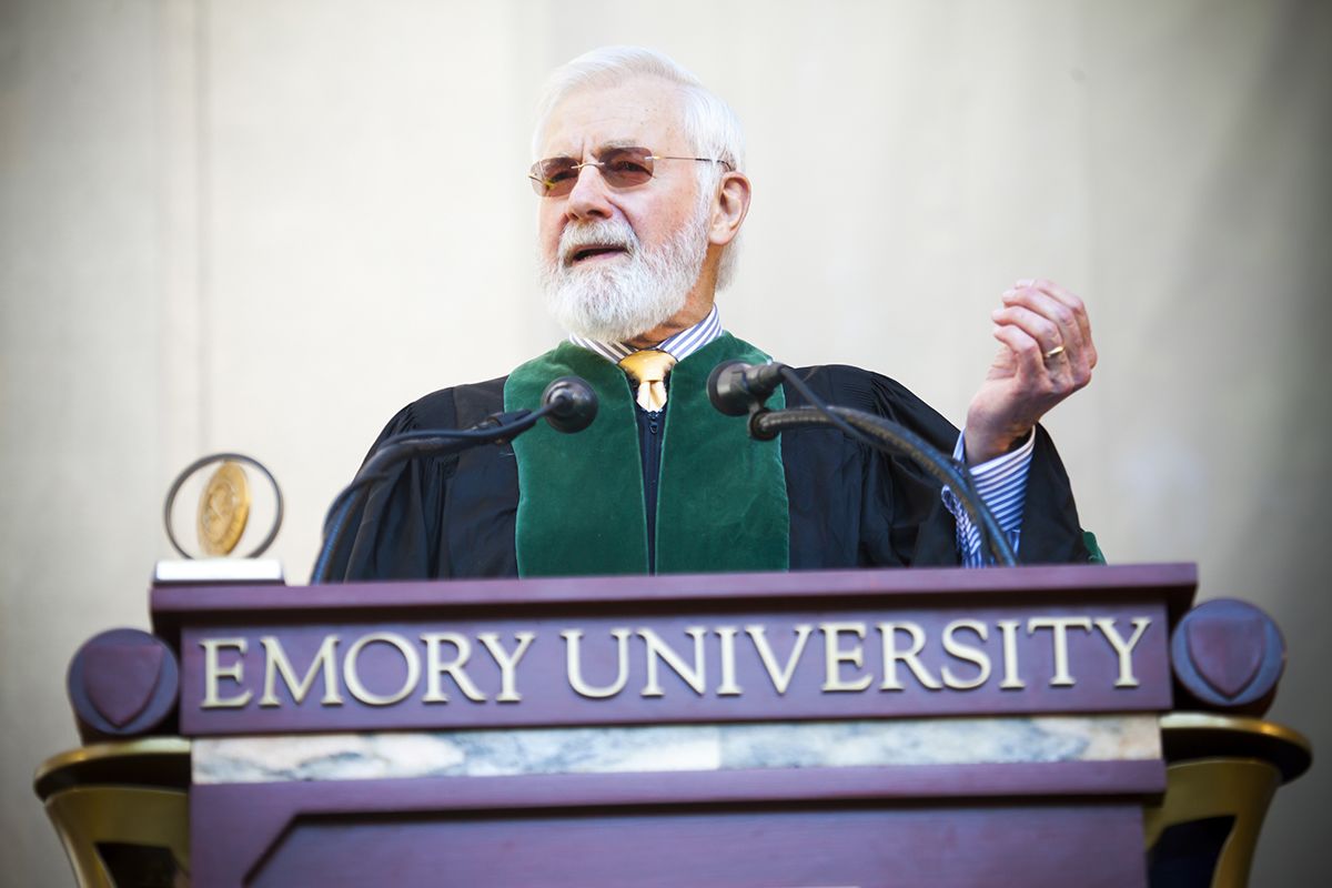 William Foege wears academic robes and speaks behind an Emory University podium
