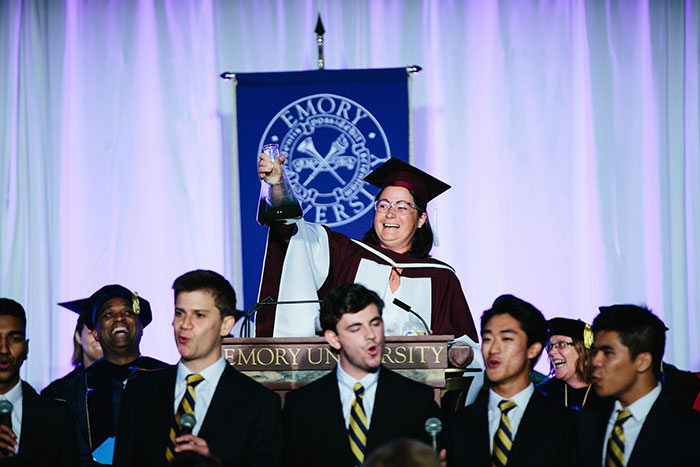 A faculty member holds a beaker high.