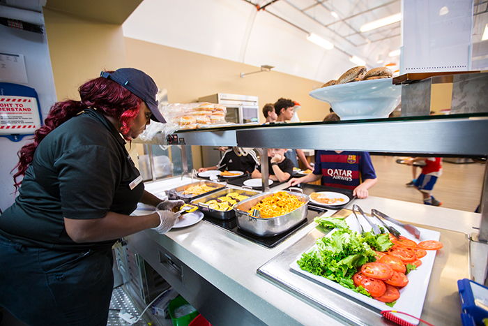 A DUCling employee serves students fresh food.