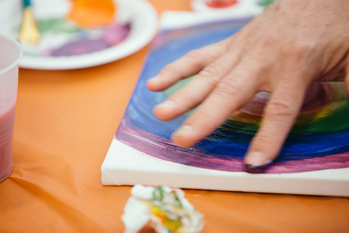 A staff member uses finger paints to create a rainbow.