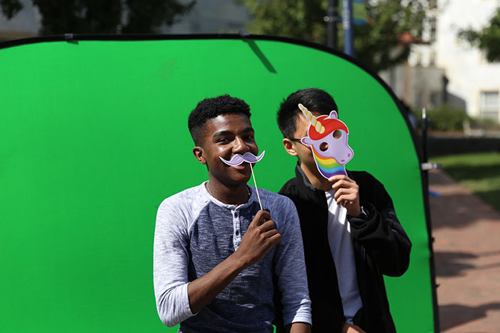Two students pose with mustache and unicorn face masks.