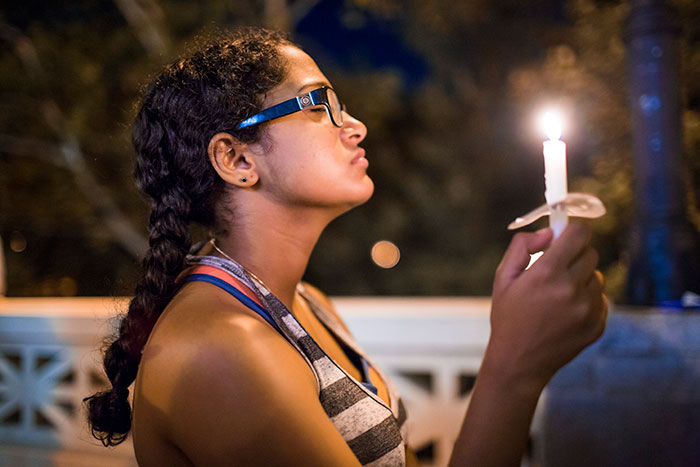 A student closes her eyes as she holds a candle high at the Oct. 4 candlelight vigil.