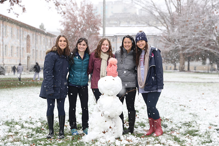 Five female students pose with a snowperson.