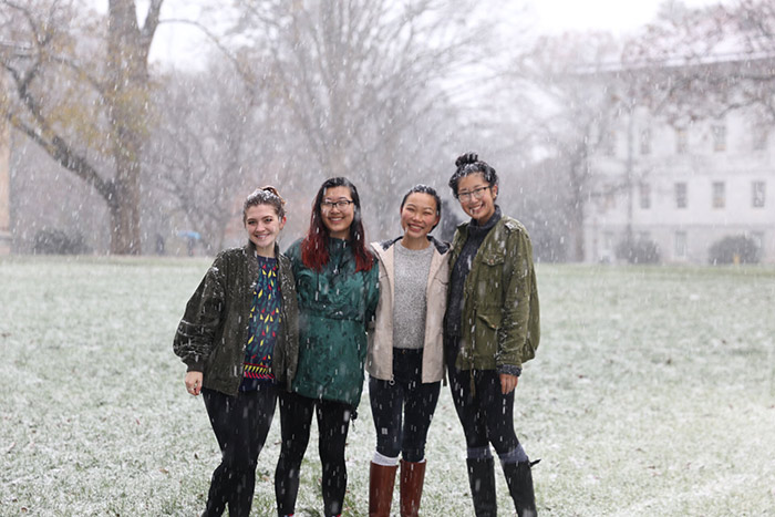 Four students pose for the camera as snow falls around them.