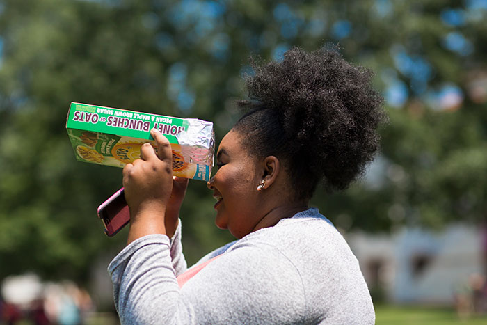 A student looks through a cereal box to experience the eclipse.