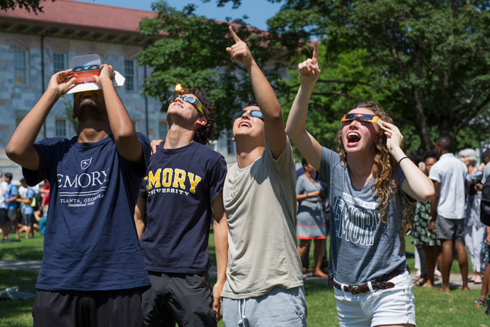 Students look through glasses at the eclipse above.