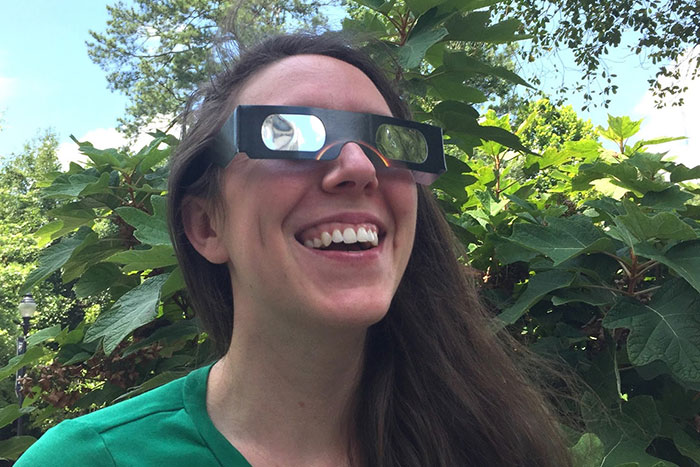 Psychology graduate student Katy Renfroe tests out a pair of solar eclipse glasses.