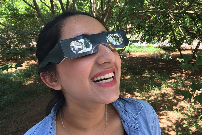 Emory senior Raveena Chhibber tests out a pair of solar eclipse glasses.