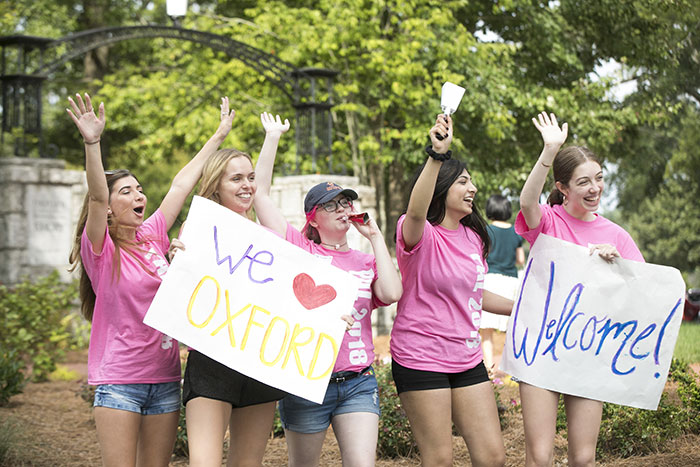 Student volunteers hold up signs welcoming new students moving in