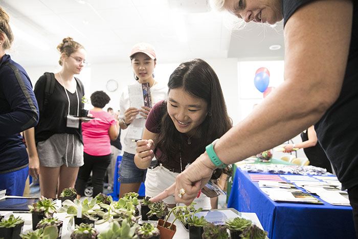A student excitedly looks at small plants in the registration area