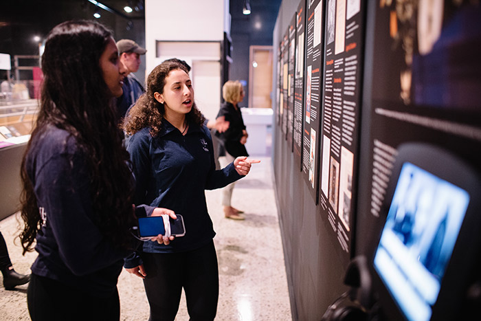 Two young women read exhibit information hung on the wall