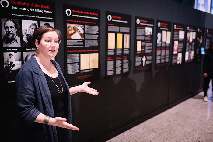 A faculty member speaks to a crowd about the exhibit