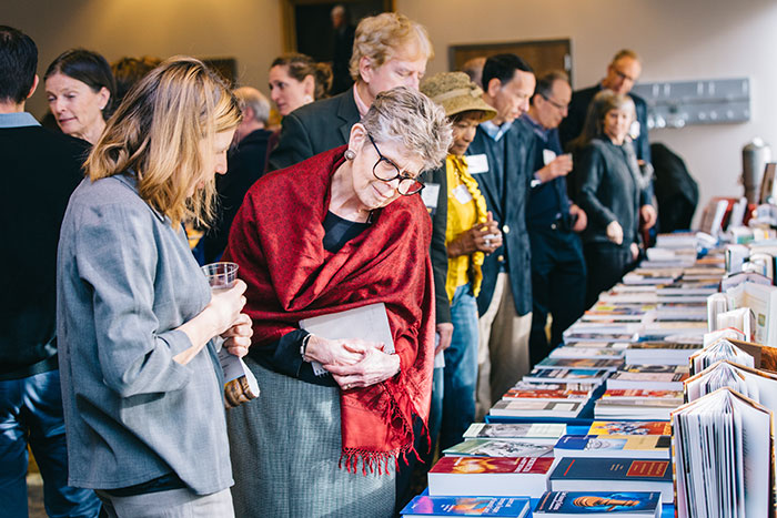 Participants look at faculty books on display at a table