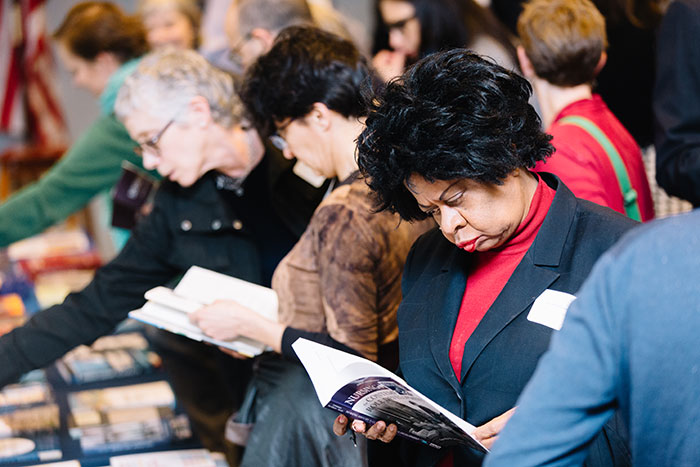 Participants skim through faculty books on display at a table