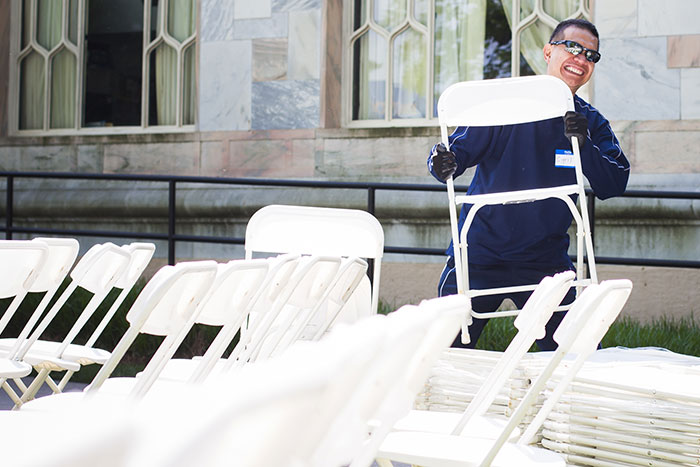 An Emory employee smiles as he grabs a folding chair from a stack