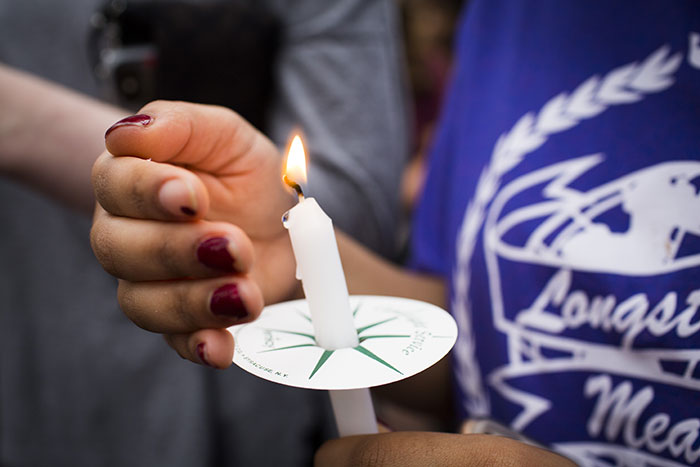 A student protects a candle from the wind at the student vigil for victims of the shooting in Parkland, Florida