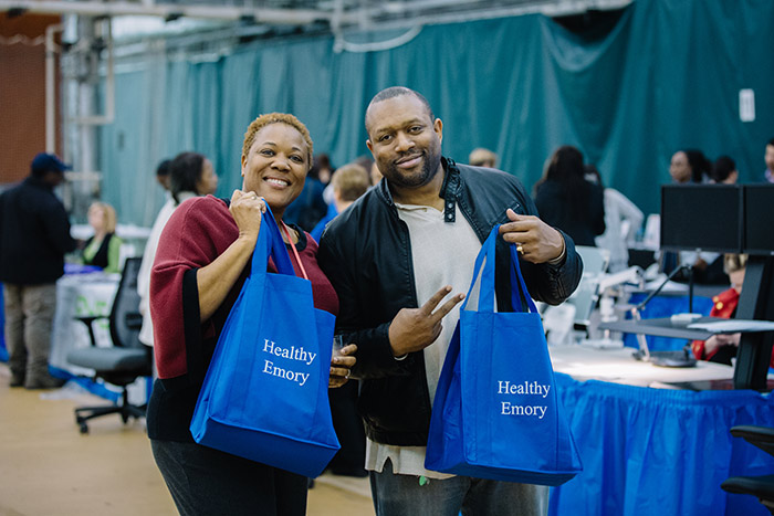 Two attendees walk around with Health Emory swag