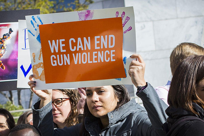 A female student holds up a sign that reads: "We can end gun violence"