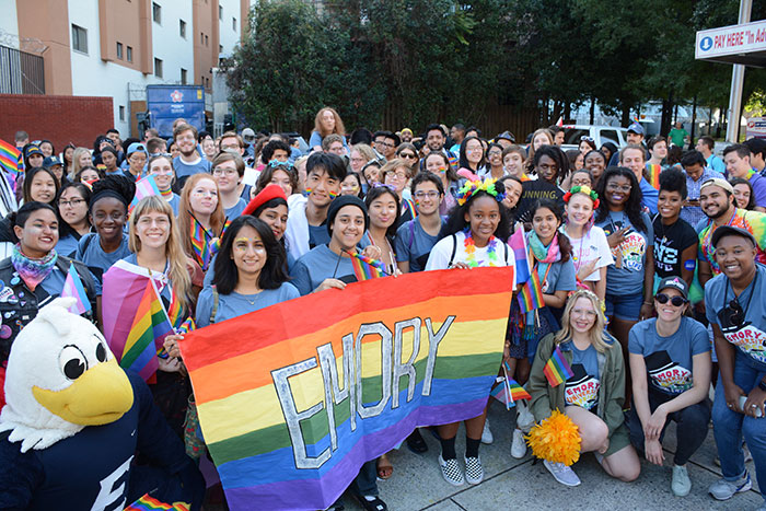 A large crowd of Emory students stand behind an Emory banner