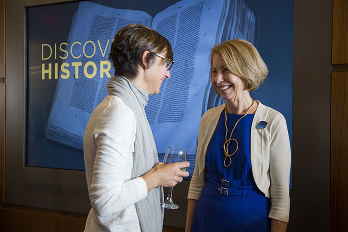 Rosemary Magee and Allison Dykes both stand in front of a projector displaying the words, "Discover History," at Magee's retirement reception.