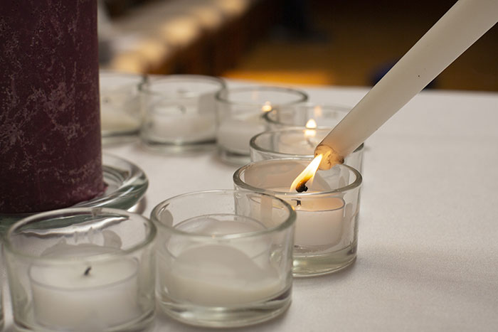 Tea light candles are lit using a white taper candle