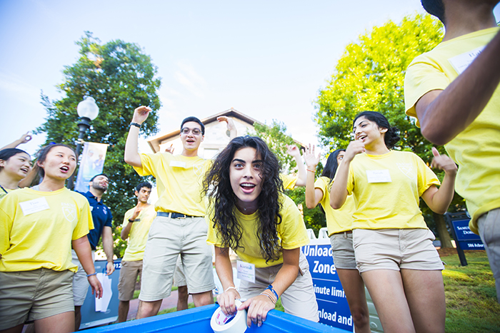Resident Assistants in matching yellow t-shirts excitedly welcome new students moving in