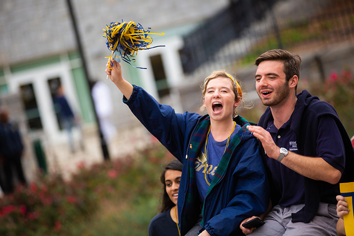 Two students cheer, waving an Emory-colored shaker