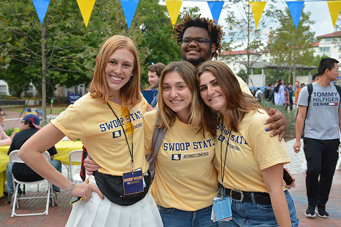 Four students wearing Homecoming shirts pose for a photo