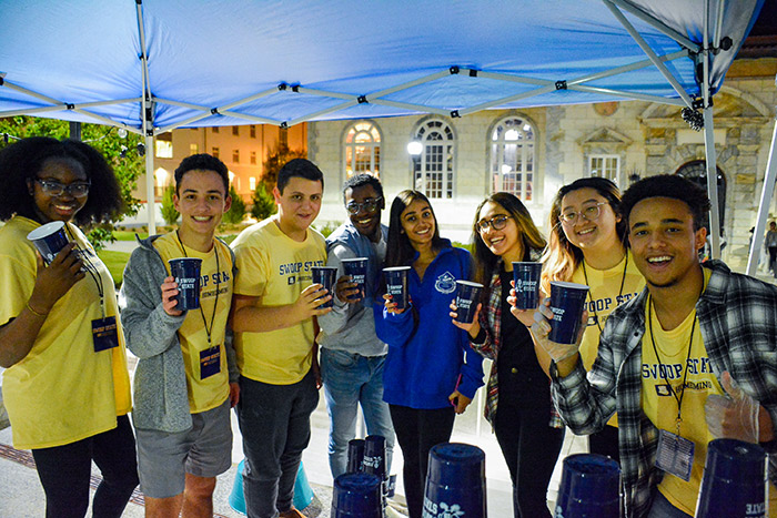 Students pose under a tent with Emory cups