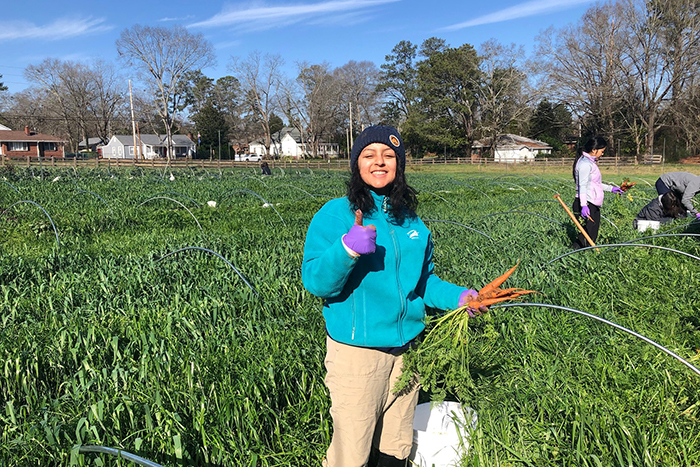 A student poses with carrots she has pulled for the MLK Day of Service