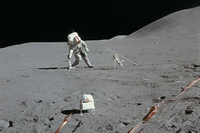 Col. David R. Scott, commander of Apollo 15, walks on the moon’s surface, bending to pick something over.