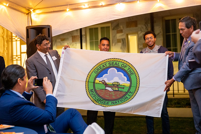 Emory Provost Bellamkonda with three other men hold up the flag of the Muscogee Nation