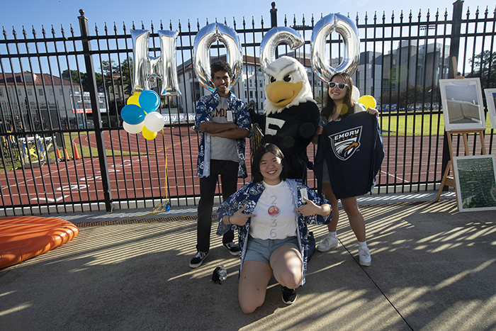 Students pose with Swoop in front of a fence that says HoCo