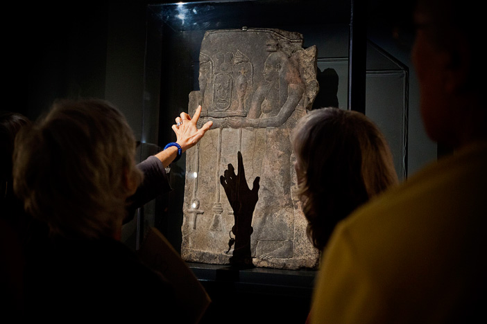 Participants look at ancient art under light. 