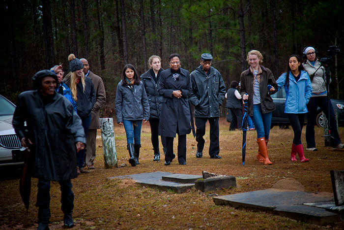 Accompanied by Emory students, Dorothy Nixon Williams (center) and her husband, Sam Williams, walk through Old Salem Cemetery to where the students found the grave of her father, Isaiah Nixon.