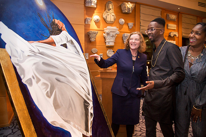 President Claire E. Sterk talks with artist and Emory PhD student Fahamu Pecou (center) about "Emerge," the painting he created to commemorate her inauguration, as his wife, Jamila Pecou, looks on.