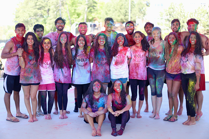 group of students posing with different color powder all over them