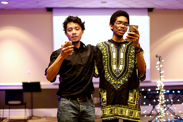 two male students reading from their phones at the microphone