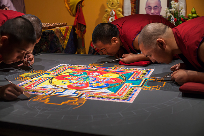Four tibetan monks working on mandala