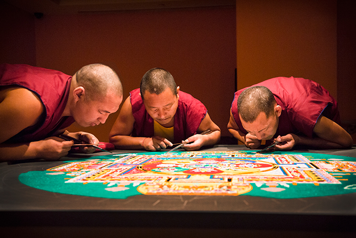 Three monks working on mandala