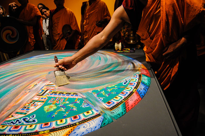 monk swiping mandala sand in swirling motion