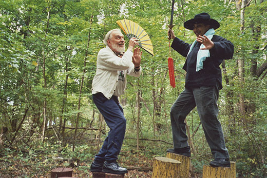 Two people battling playfully on tree stumps