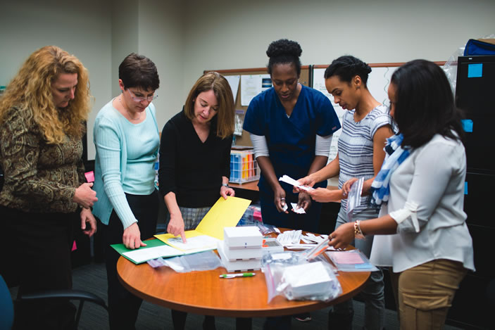 Nursing school faculty and students prepare kits used to collect samples from mothers and babies.