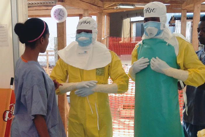 Amelie Cardon 12MPH, left, checks the protective gear of people going into an Ebola treatment area in Moyamba, Sierra Leone. 