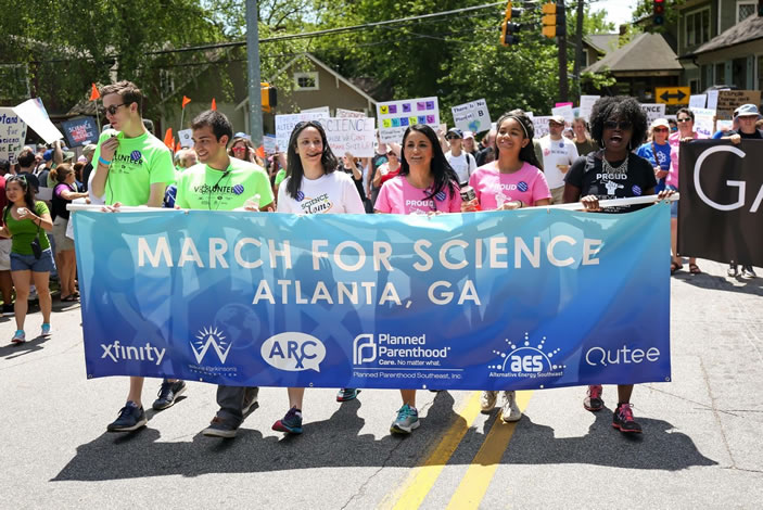 March for Science banner at the front of the parade, with march director Jasmine Clark on the right