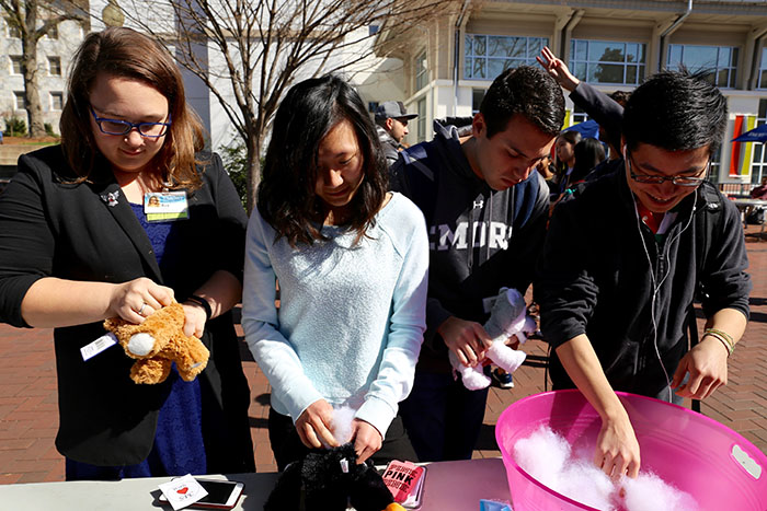 Four students stand at a table making toy valentines animals.