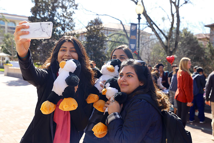 Three female students take a selfie with their toy animals.
