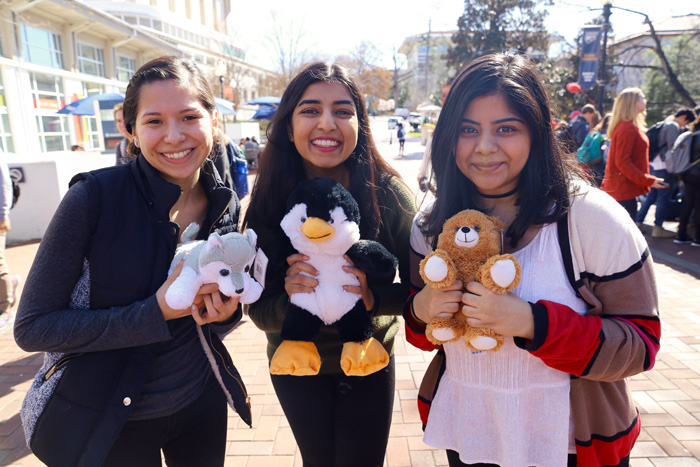 Three female students pose with toy animals they made.
