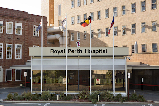 A sign reads 'Royal Perth' Hospital with four flags flying out front